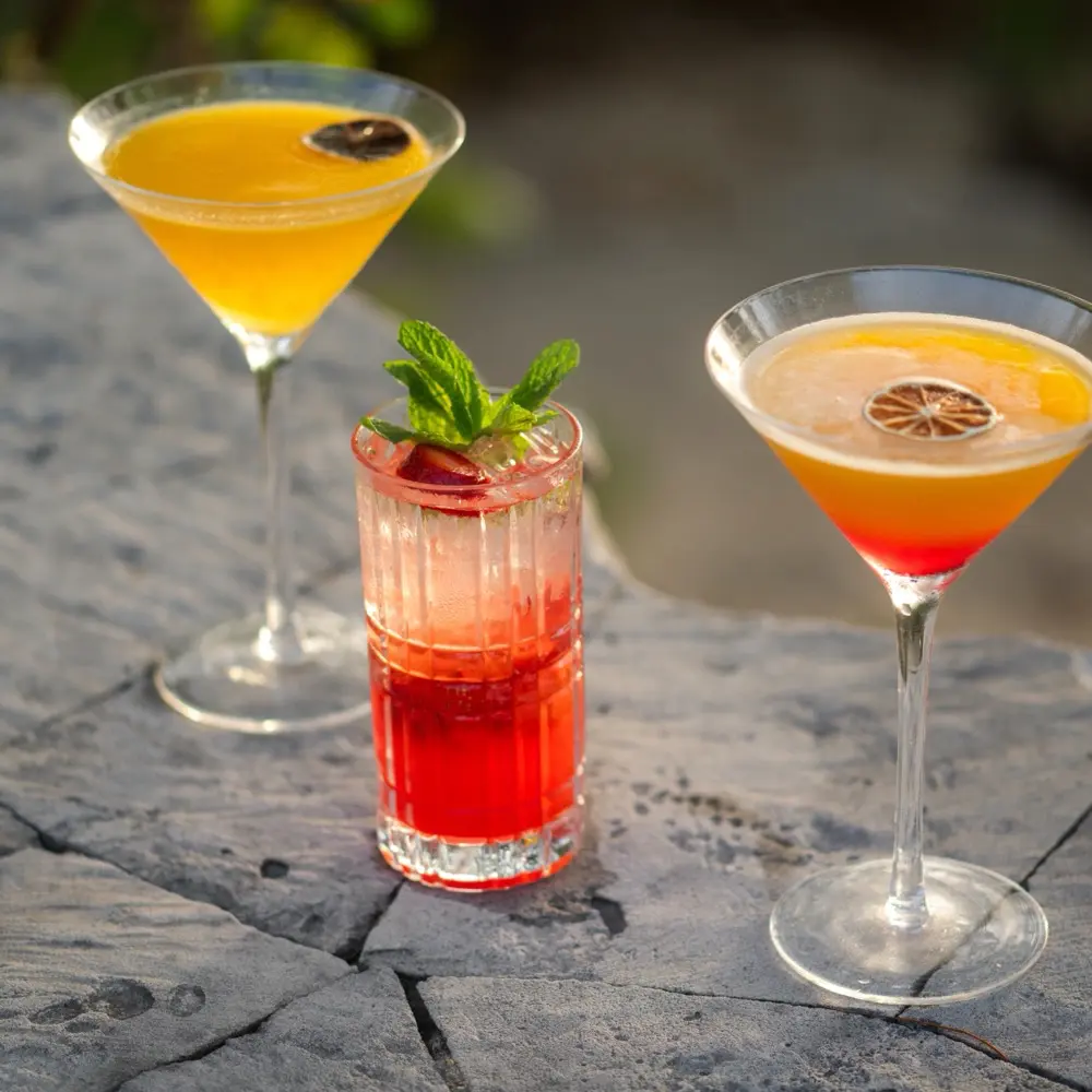 Three colorful cocktails on a stone surface