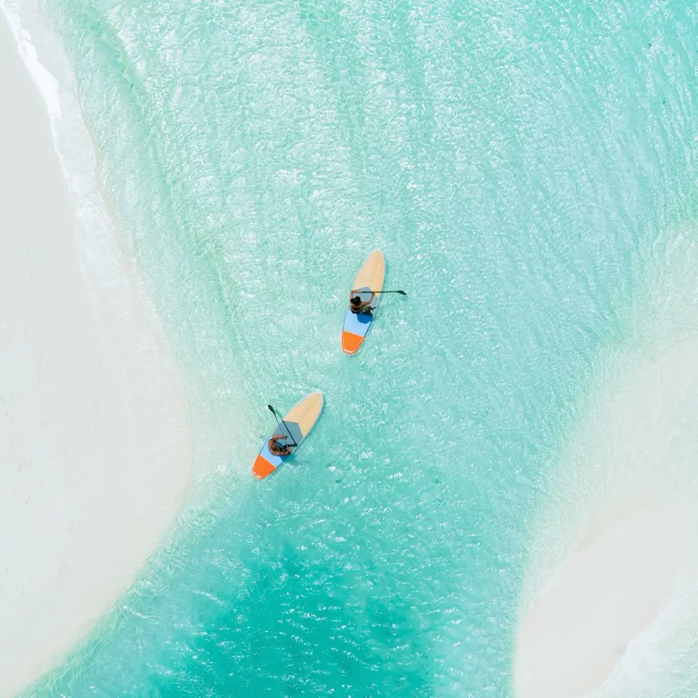 Aerial view of two paddleboarders over turquoise water